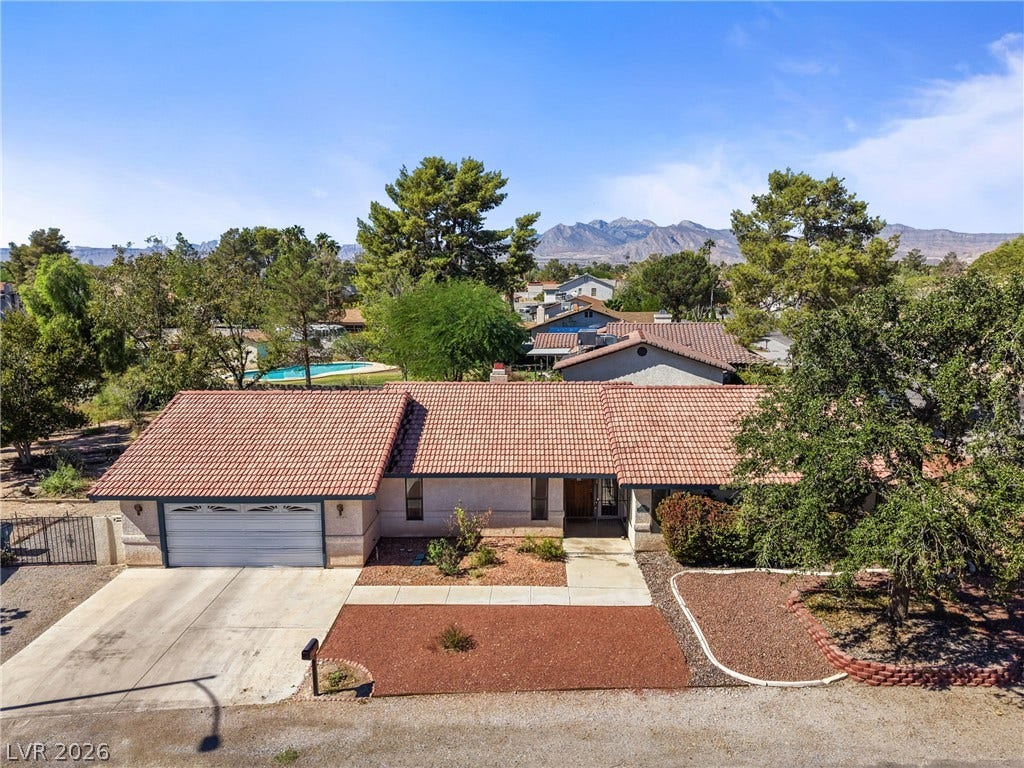 5601 Paseo Recallo Court, Las Vegas, NV 89108 A classic tile roof and concrete driveway define this single-level home against a mountain backdrop.