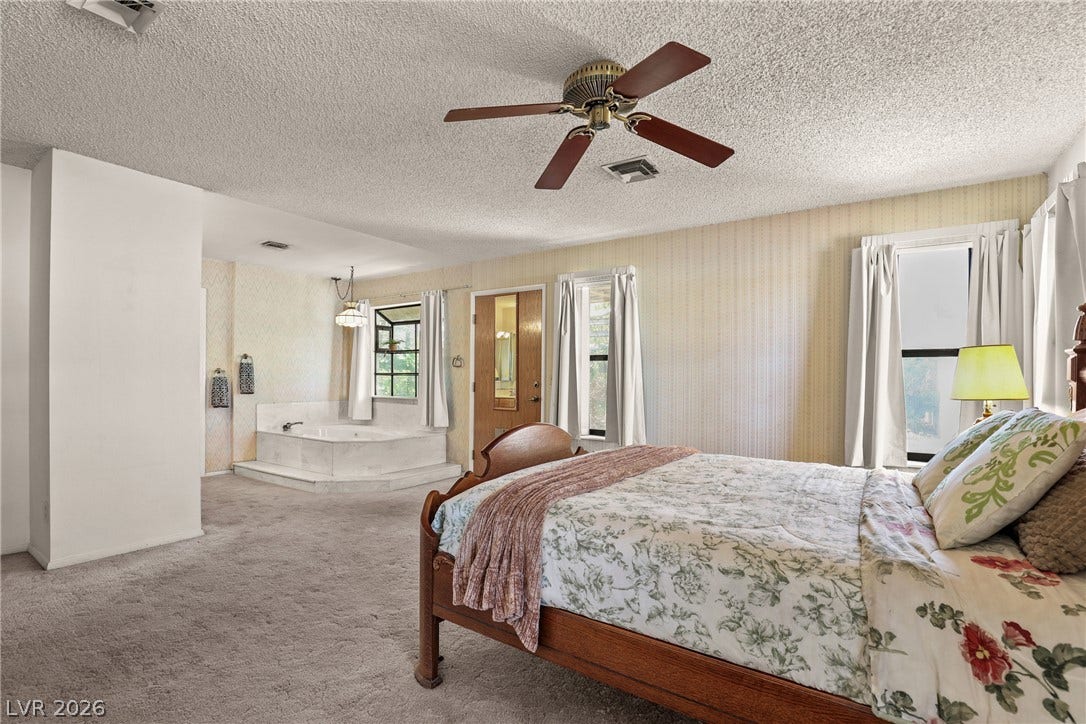5601 Paseo Recallo Court, Las Vegas, NV 89108 Plentiful windows fill this bedroom suite containing a raised soaking tub area with soft carpet flooring.