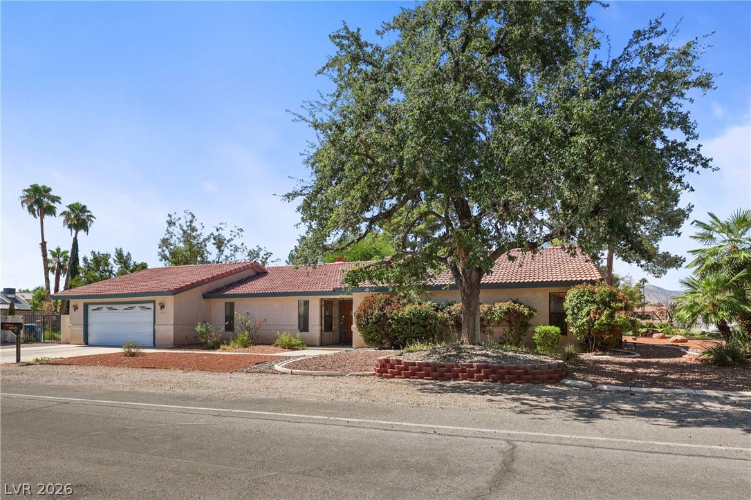 5601 Paseo Recallo Court, Las Vegas, NV 89108 Mature shade trees and a classic tile roof frame this charming single-story ranch home.