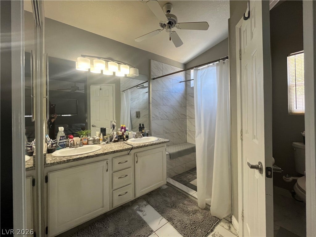 15 Rue des Champs, Henderson, NV 89074 A spacious vanity with dual sinks anchors this modern bathroom featuring tiled finishes throughout.