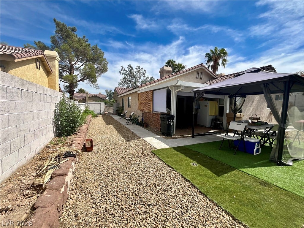 15 Rue des Champs, Henderson, NV 89074 An inviting backyard features a gravel side yard alongside a covered patio and artificial turf.
