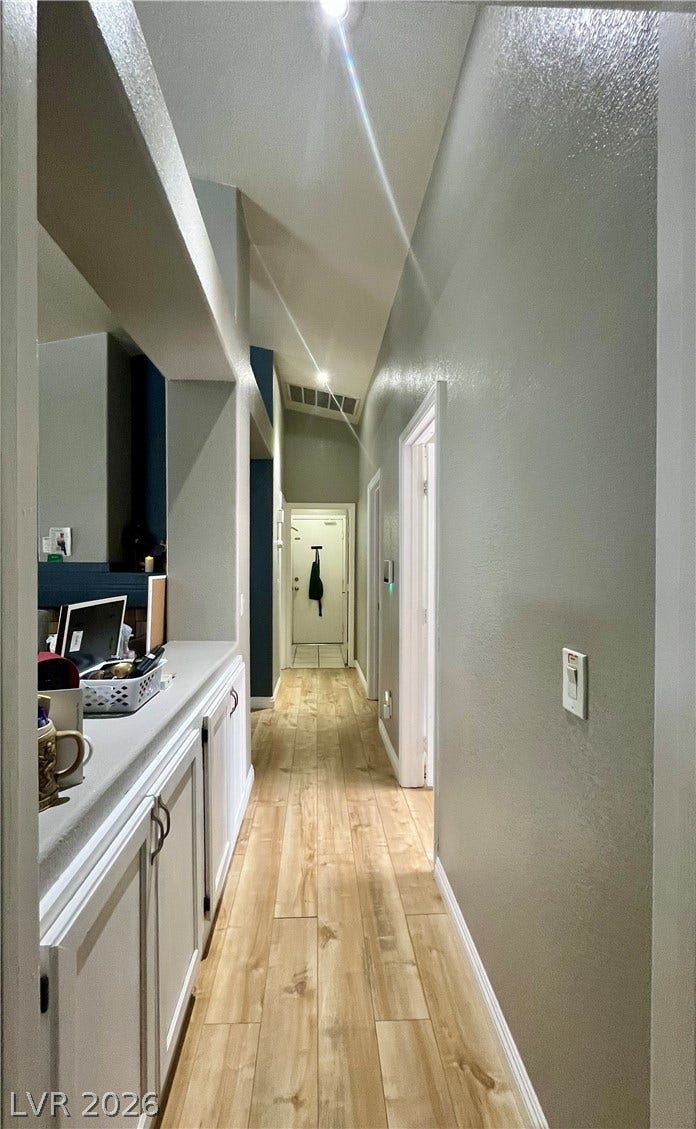 15 Rue des Champs, Henderson, NV 89074 Warm wood flooring and vaulted ceilings frame a long hallway lined with built-in cabinetry.