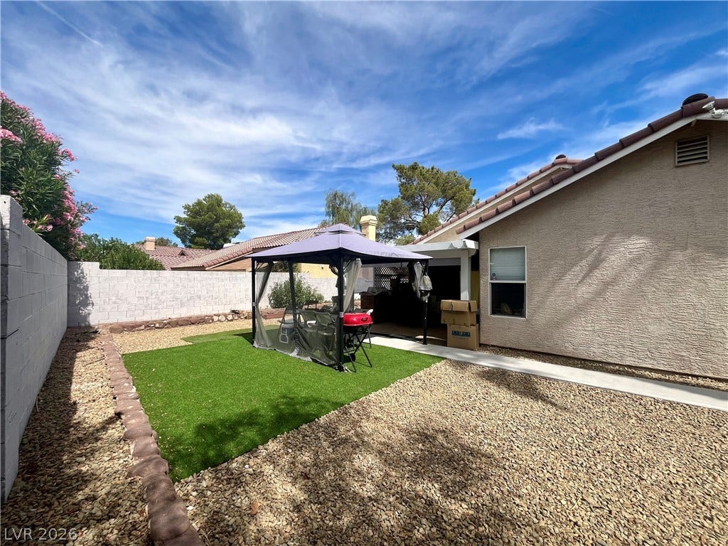 15 Rue des Champs, Henderson, NV 89074 An inviting backyard features low-maintenance gravel landscaping and a neat patch of green turf.