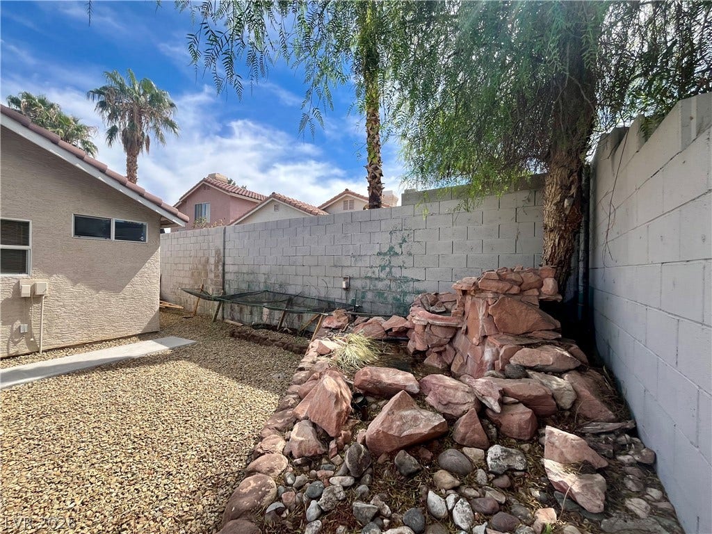 15 Rue des Champs, Henderson, NV 89074 Mature trees shade a low-maintenance stone rock feature and gravel side yard.