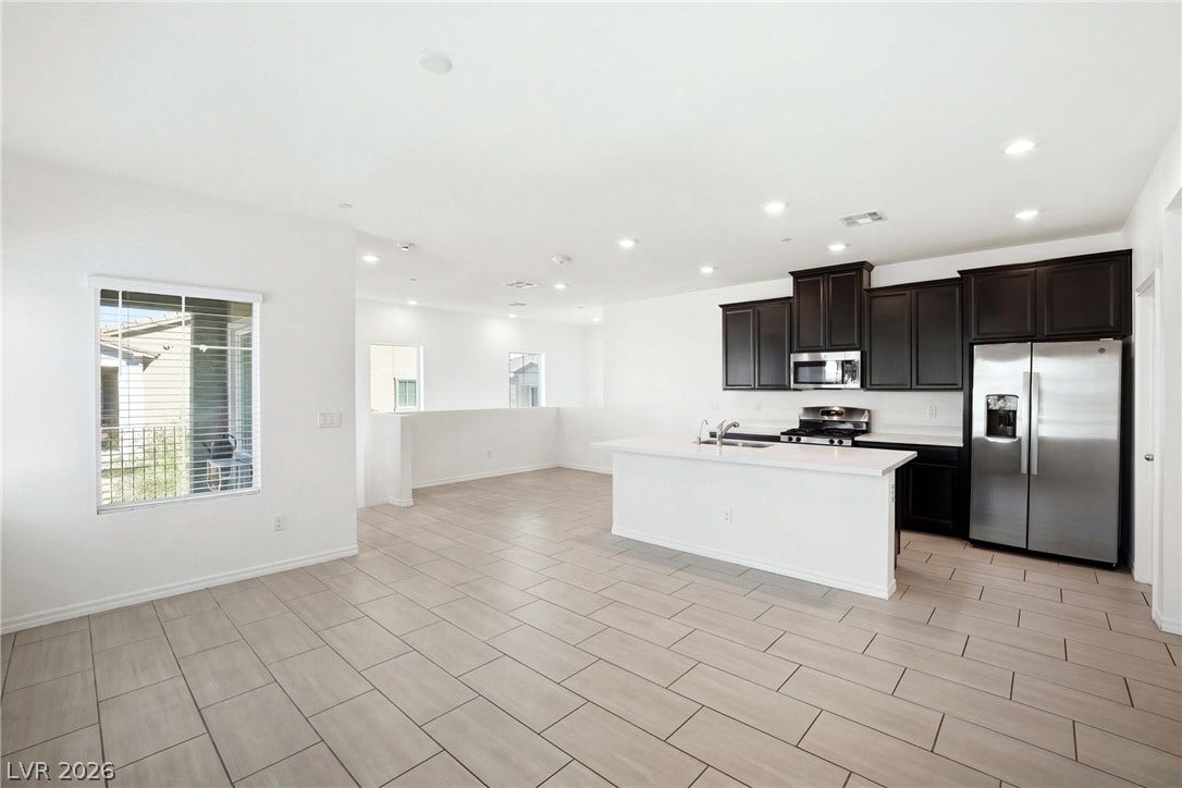 Gleaming tile floors and dark cabinetry define this open kitchen and dining layout.