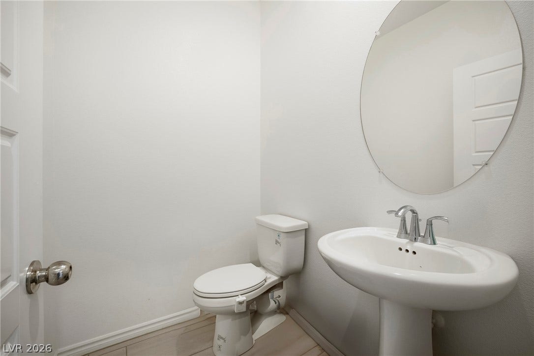 A classic pedestal sink paired with neutral flooring creates a clean powder room design.