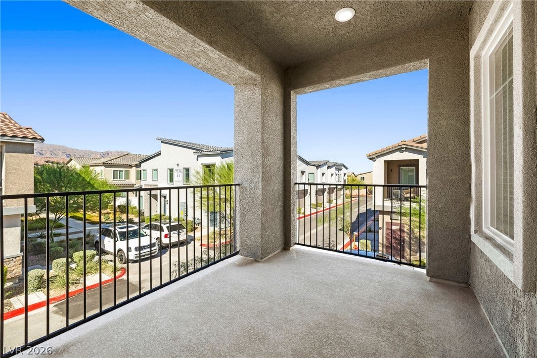 An elevated private balcony overlooks the neighborhood with stucco columns and recessed ceiling light.