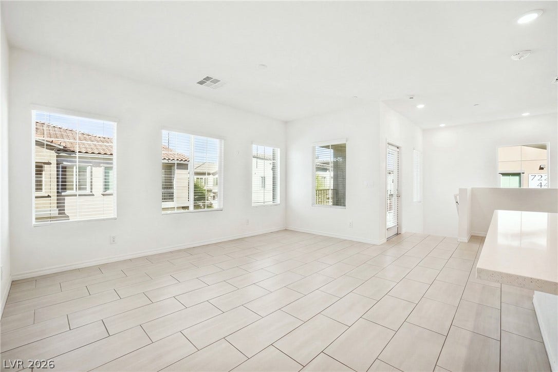 A spacious layout seamlessly connects clean-lined tiled flooring with multi-window views of the surrounding neighborhood.