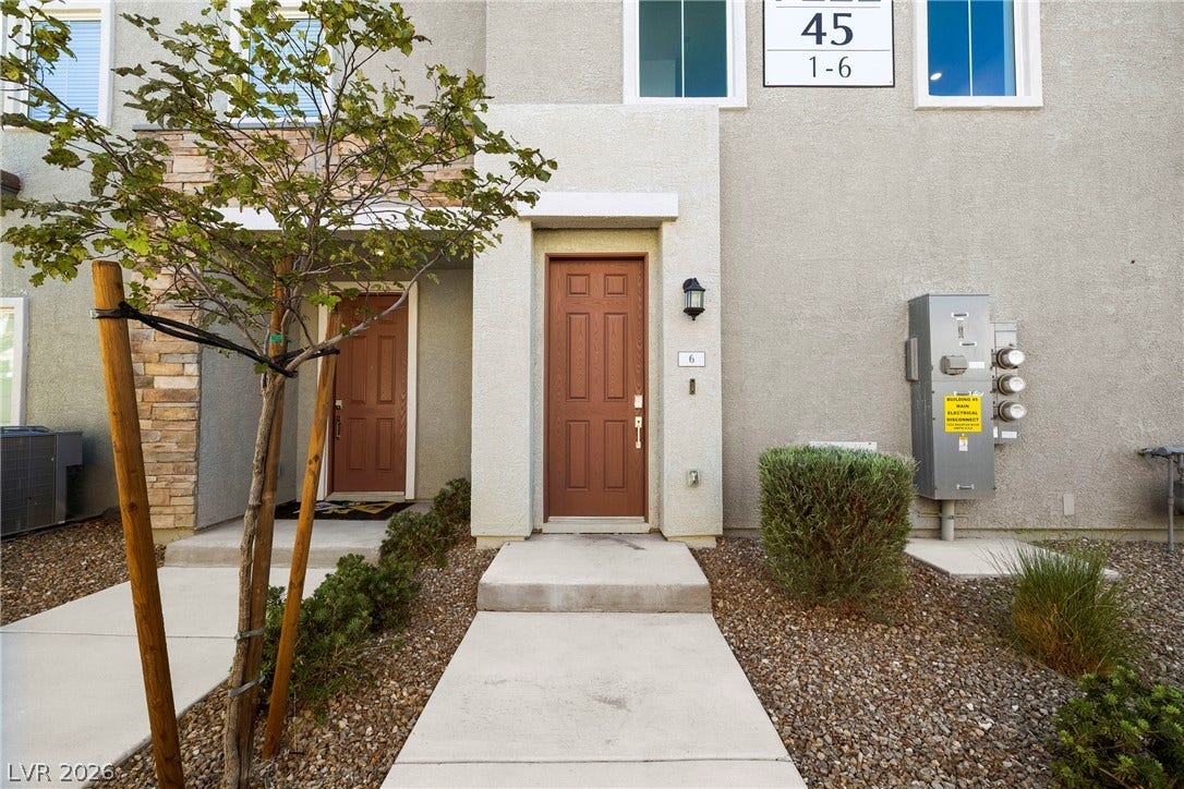 A concrete walkway leads directly to the front entrance of this multi-level stucco home.