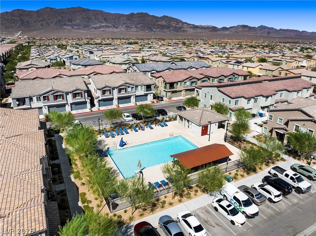 An inviting community swimming pool sits nestled within a modern residential neighborhood set against mountains.