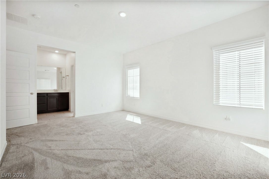 Plush carpeting and natural light define this master bedroom featuring an attached bathroom access.
