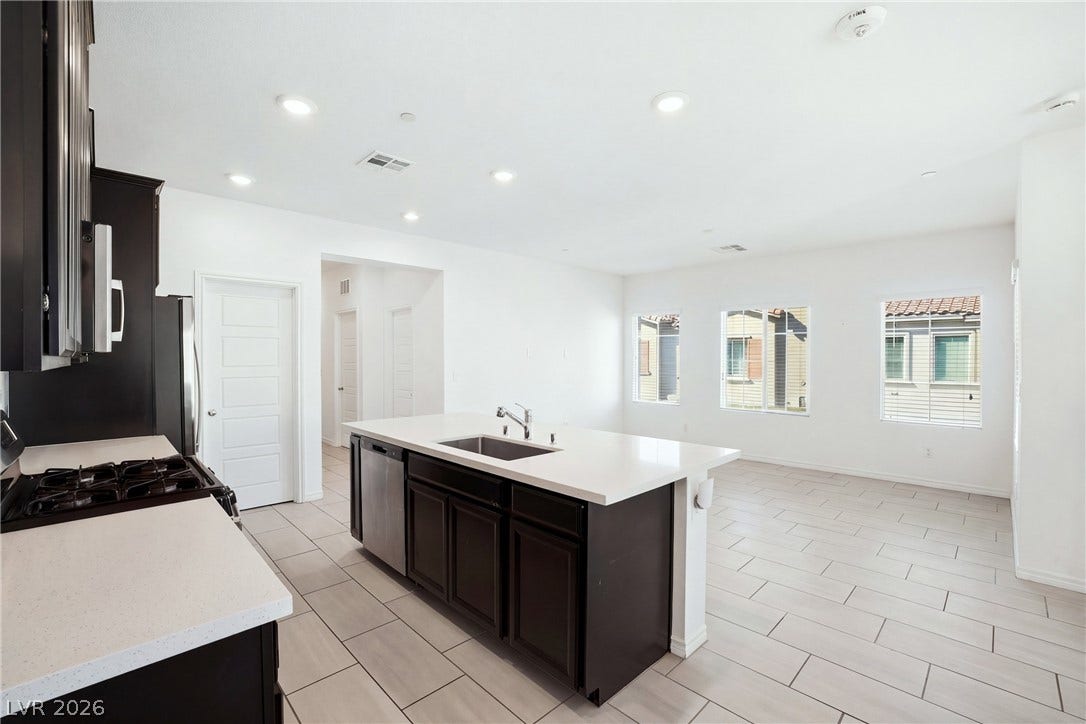 An open kitchen layout flows seamlessly into a dining area over tiled flooring.