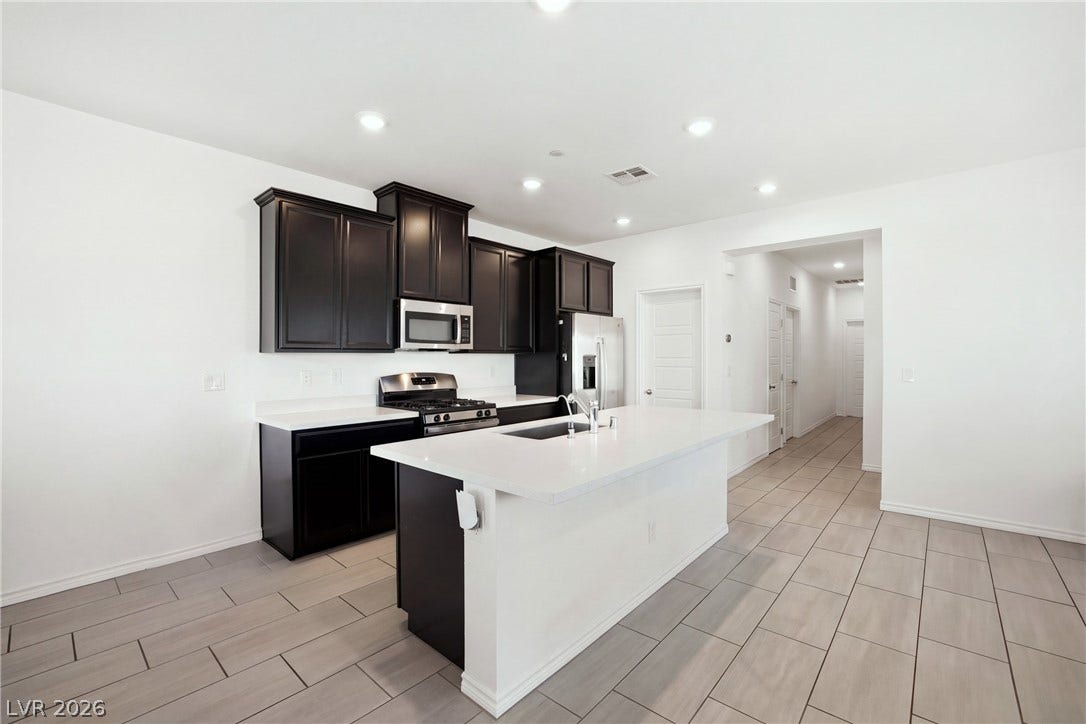 A spacious central island highlights this contemporary kitchen featuring crisp white countertops and tile flooring.