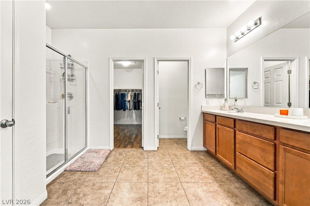 4209 Fairywren Drive, North Las Vegas, NV 89031 An expansive vanity with warm wood cabinets anchoring this tiled bath layout.