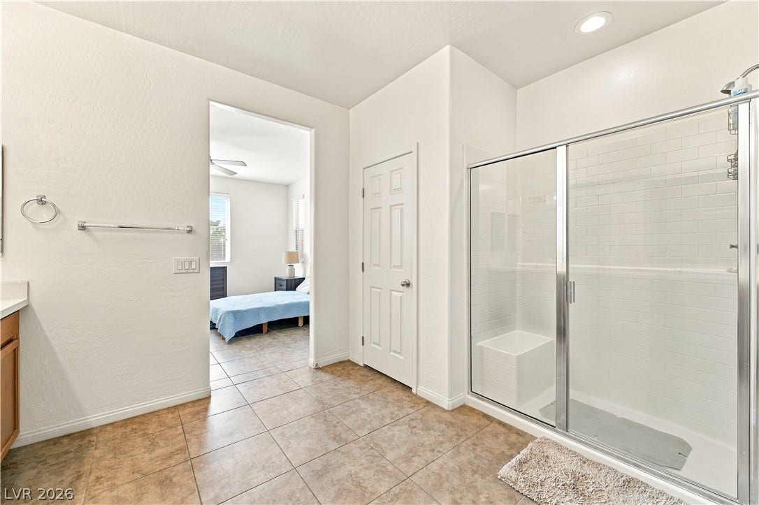 4209 Fairywren Drive, North Las Vegas, NV 89031 Tiled flooring and a glass-enclosed walk-in shower highlight this modern bathroom design.