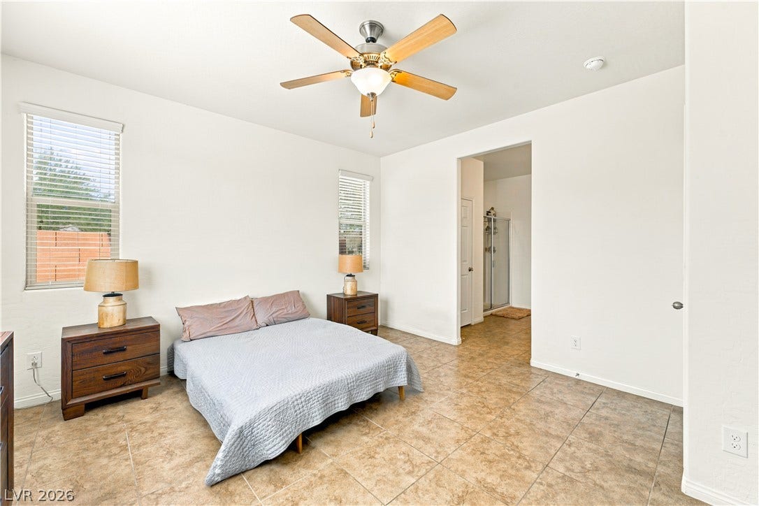 4209 Fairywren Drive, North Las Vegas, NV 89031 High ceilings and tile floors define this airy bedroom space with an attached bathroom.
