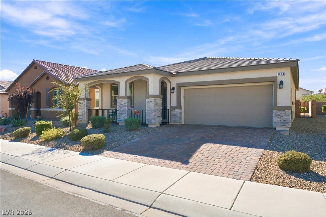 4209 Fairywren Drive, North Las Vegas, NV 89031 An inviting stone-accented exterior displays a paver driveway, arched front porch, and modern desert landscaping.