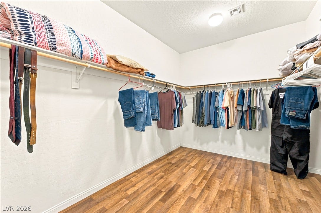 4209 Fairywren Drive, North Las Vegas, NV 89031 Ample hanging rods and shelving optimize storage within a spacious walk-in closet featuring warm wood floors.