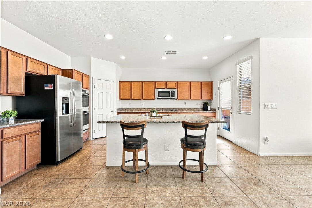 4209 Fairywren Drive, North Las Vegas, NV 89031 An open kitchen layout showcases classic tile flooring and a central granite-topped island.