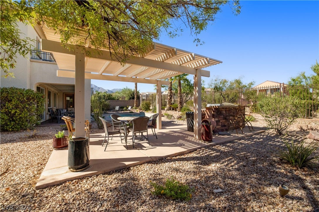 926 Loma Bonita Place, Las Vegas, NV 89138 An open pergola shades a concrete patio alongside a built-in outdoor kitchen structure.