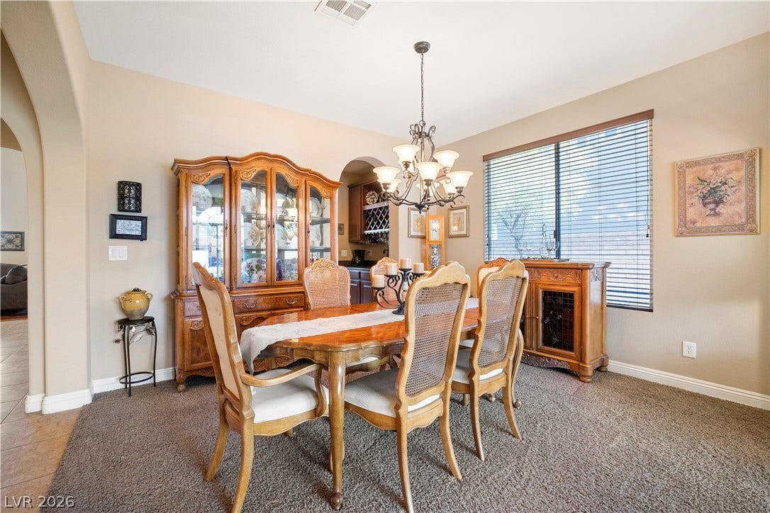 926 Loma Bonita Place, Las Vegas, NV 89138 An elegant dining space features plush carpeting, an arched entryway, and a classic chandelier fixture.