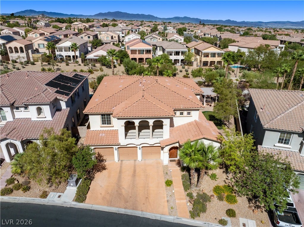 926 Loma Bonita Place, Las Vegas, NV 89138 An aerial perspective showcases a tile roof home surrounded by neighborhood views and mountain backdrops.