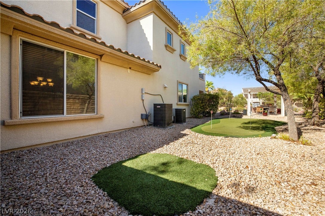 926 Loma Bonita Place, Las Vegas, NV 89138 Manicured desert landscaping frames a private backyard putting green beside the stucco exterior.