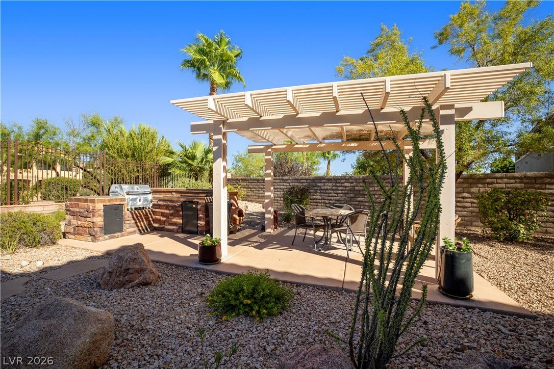 926 Loma Bonita Place, Las Vegas, NV 89138 A spacious concrete patio rests beneath a classic wooden pergola alongside a built-in stone barbecue.