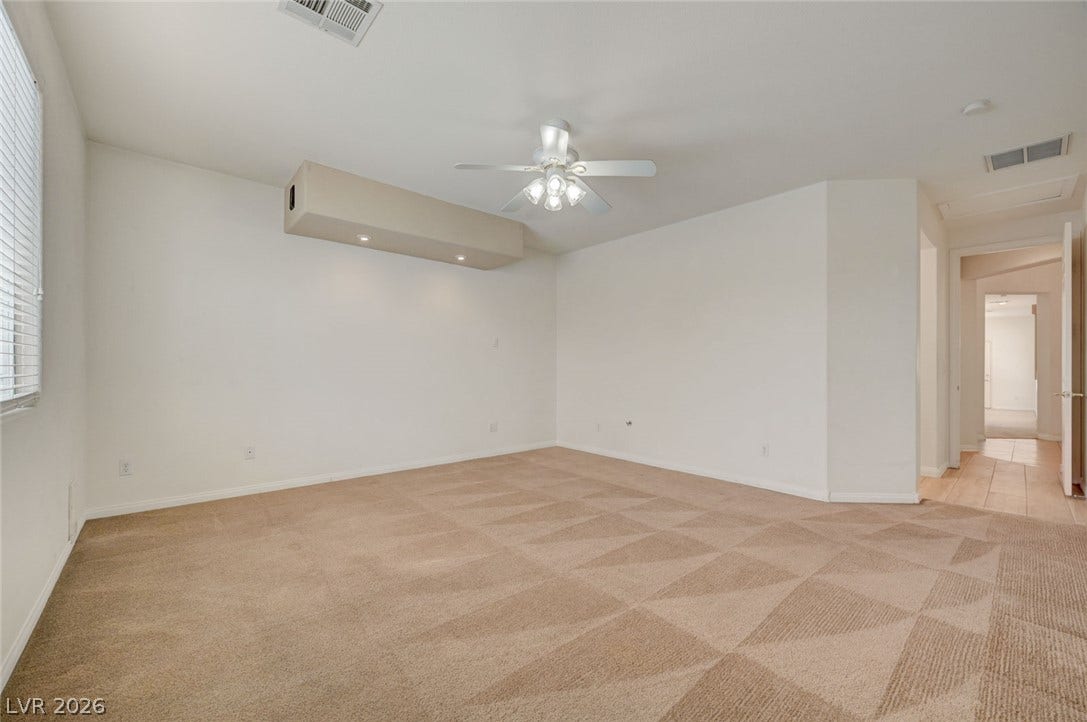 849 Ashford Way, Henderson, NV 89015 A spacious, naturally illuminated room featuring warm carpet flooring and a ceiling fan.