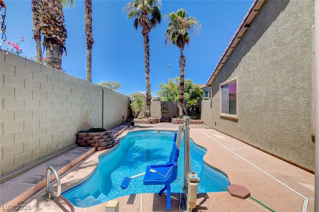 849 Ashford Way, Henderson, NV 89015 An inviting backyard features a sparkling in-ground pool, complemented by tall palm trees and a privacy wall.