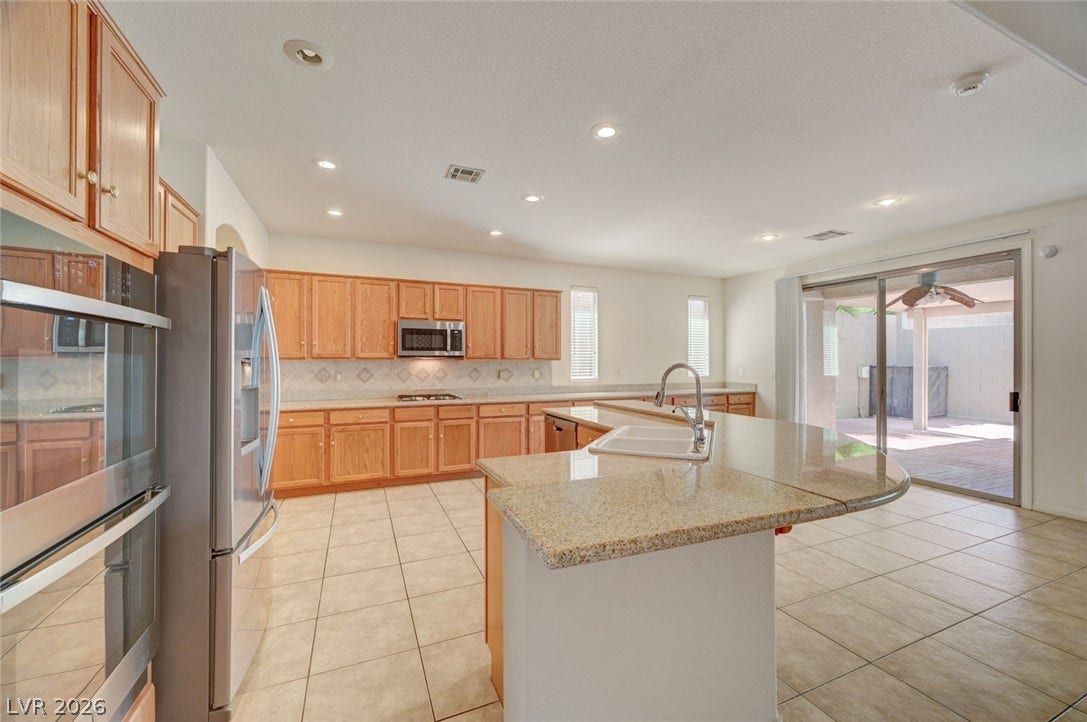 849 Ashford Way, Henderson, NV 89015 An inviting kitchen with a central island and light wood cabinetry opens to a private patio.