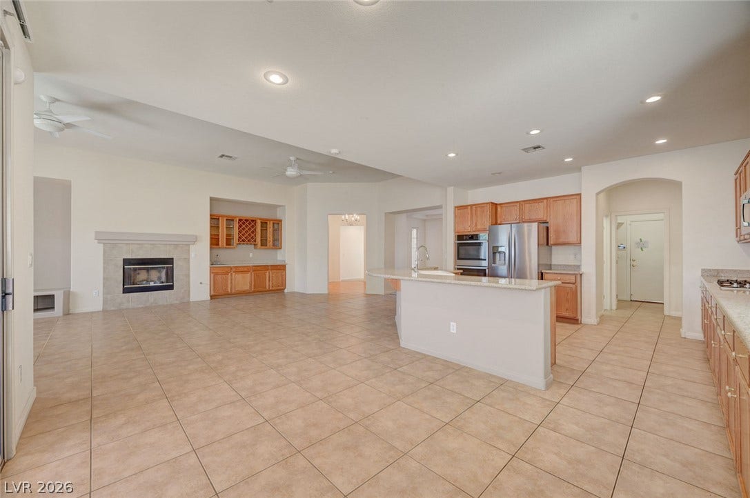 849 Ashford Way, Henderson, NV 89015 An inviting open-concept area combines kitchen, living, and dining with a cozy fireplace and convenient wet bar.