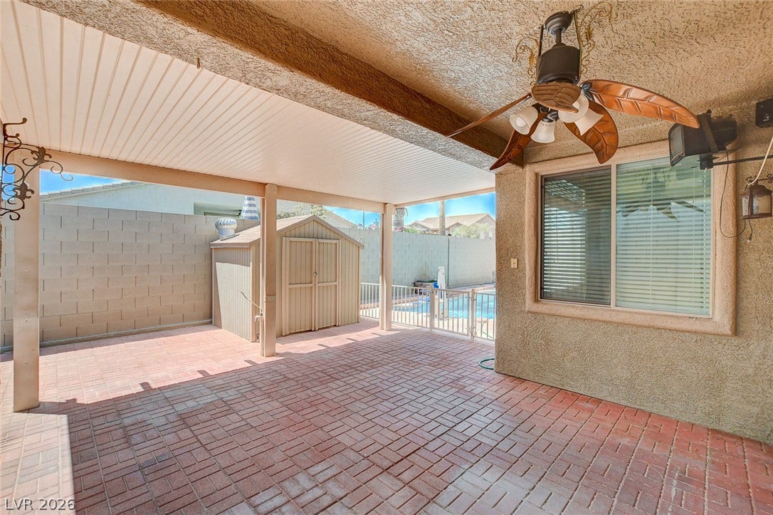 849 Ashford Way, Henderson, NV 89015 A shaded patio with brick pavers offers a delightful outdoor living space overlooking the fenced pool and backyard storage shed.