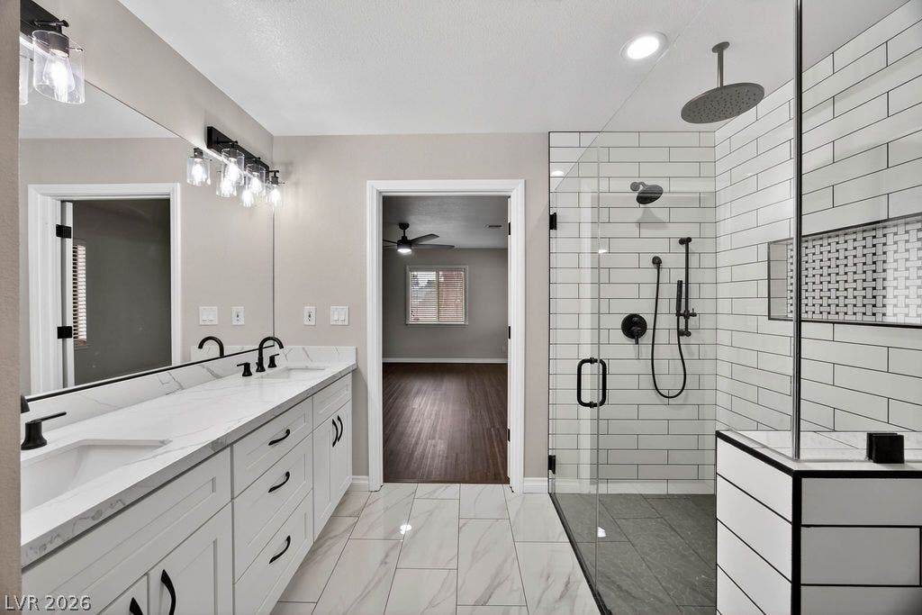 3189 Casanova Circle, Las Vegas, NV 89120 A glass-enclosed walk-in shower and stone-counter vanity highlight this beautifully updated primary bathroom.