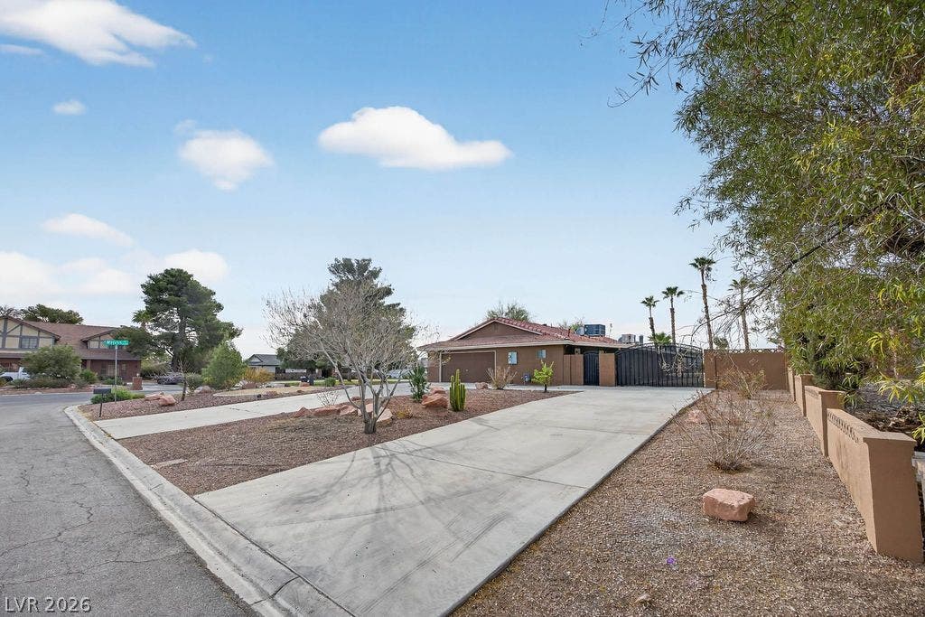 3189 Casanova Circle, Las Vegas, NV 89120 RV DRIVE WAY TO -A spacious concrete driveway leads toward the gated entrance of this single-story desert residence.