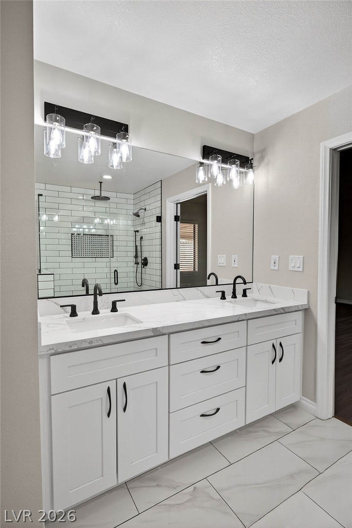 3189 Casanova Circle, Las Vegas, NV 89120 Clean lines and stone counters highlight this updated dual vanity bathroom with tiled flooring.