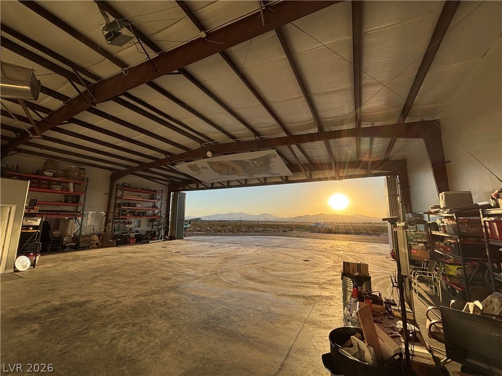 A spacious hangar framing vast mountain views and a brilliant sunset through its wide opening.