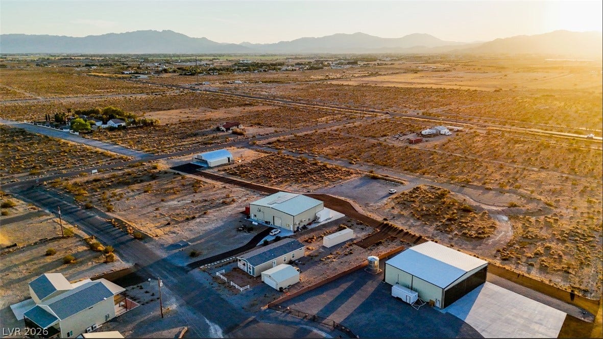 A vast desert landscape surrounds this property with expansive mountain views under a golden sky.