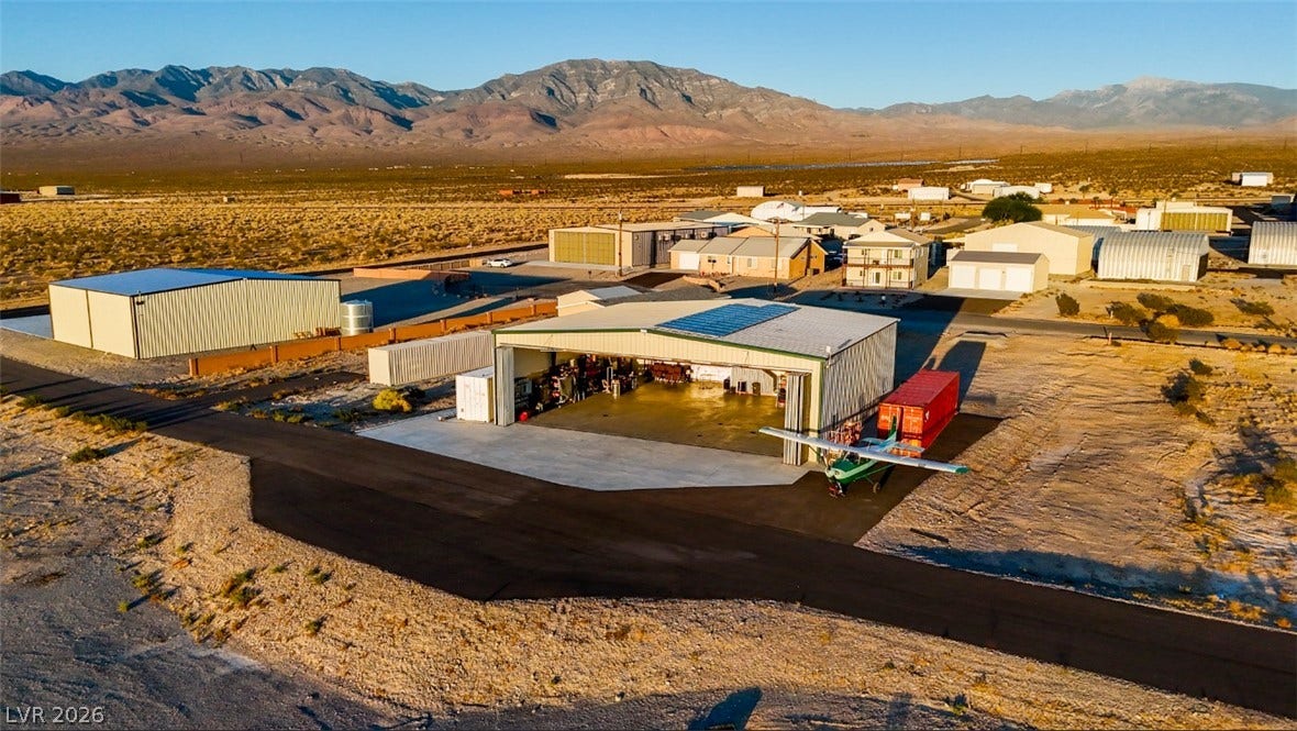 Industrial outbuildings sit nestled against a sweeping backdrop of rugged mountain ranges and desert terrain.