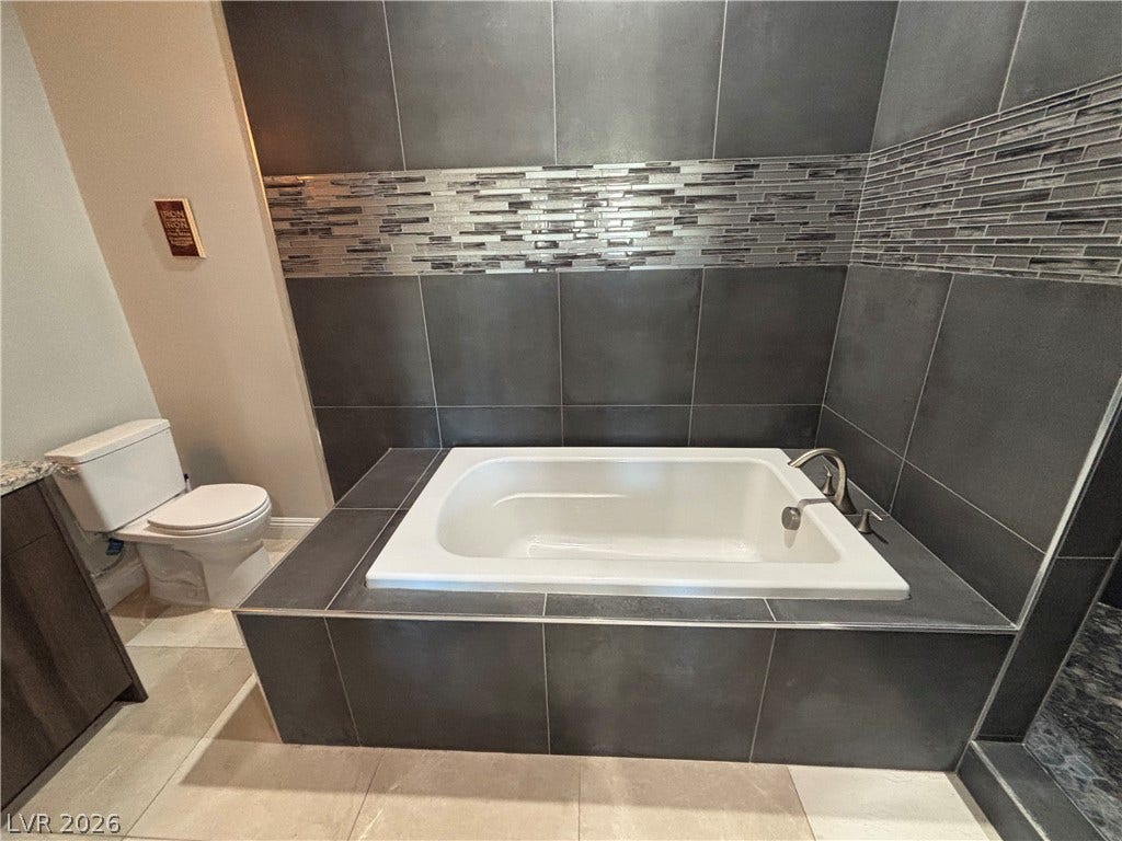 Dark tile surrounds a deep soaking tub, creating a modern and relaxing bathroom alcove.
