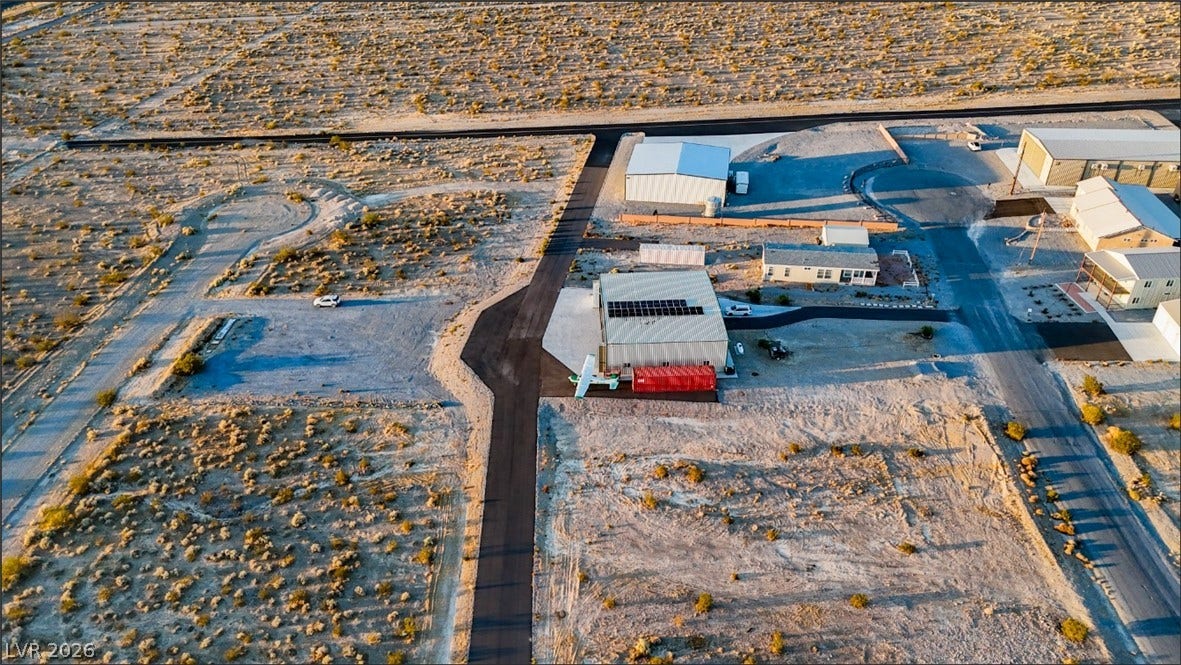Sunlight sweeps across an expansive desert landscape surrounding several properties and unpaved roads.