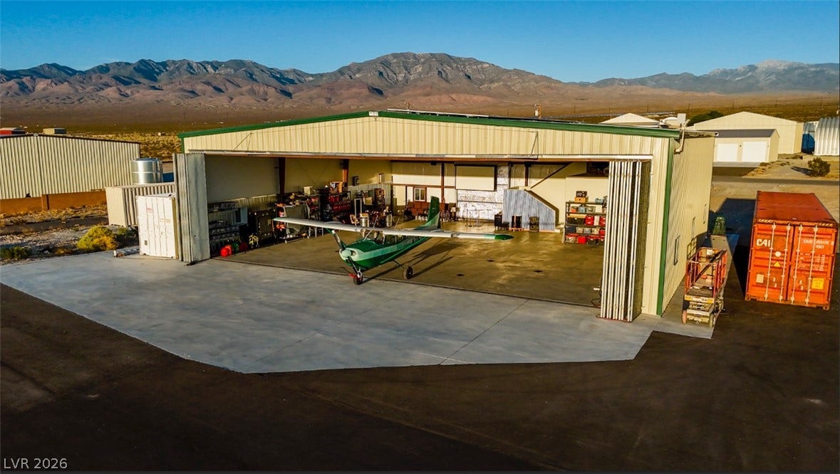 An expansive aircraft hangar showcases durable concrete flooring against a majestic mountain backdrop.
