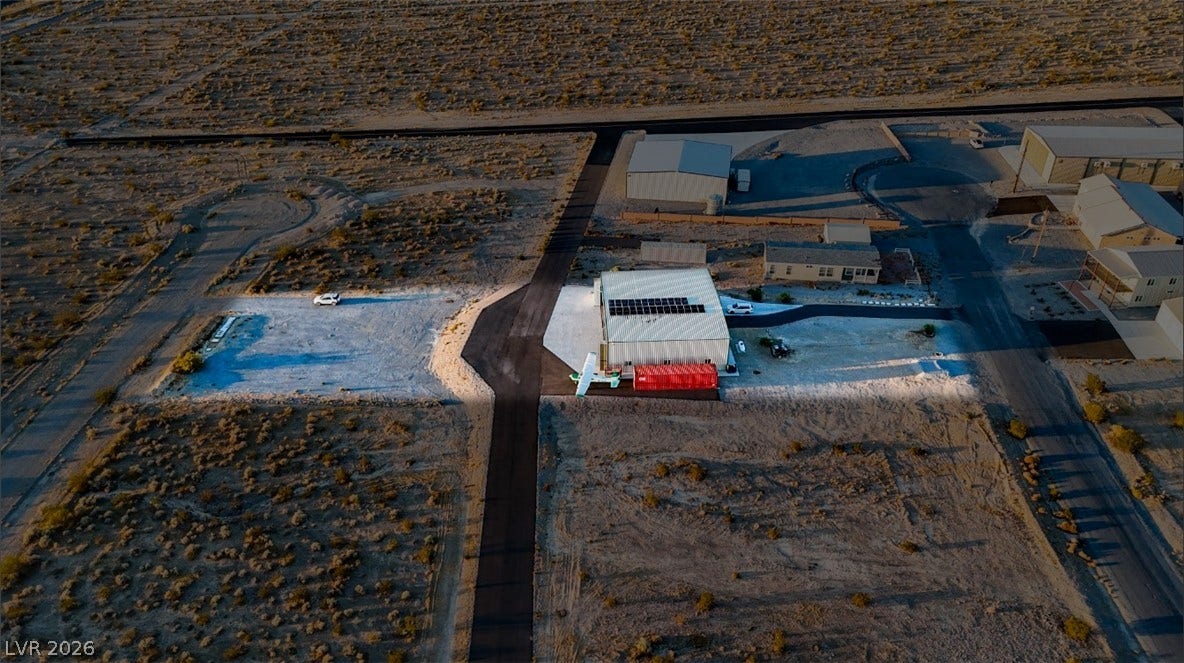 An aerial perspective reveals the metal hangar roof equipped with solar panels amidst desert surroundings.