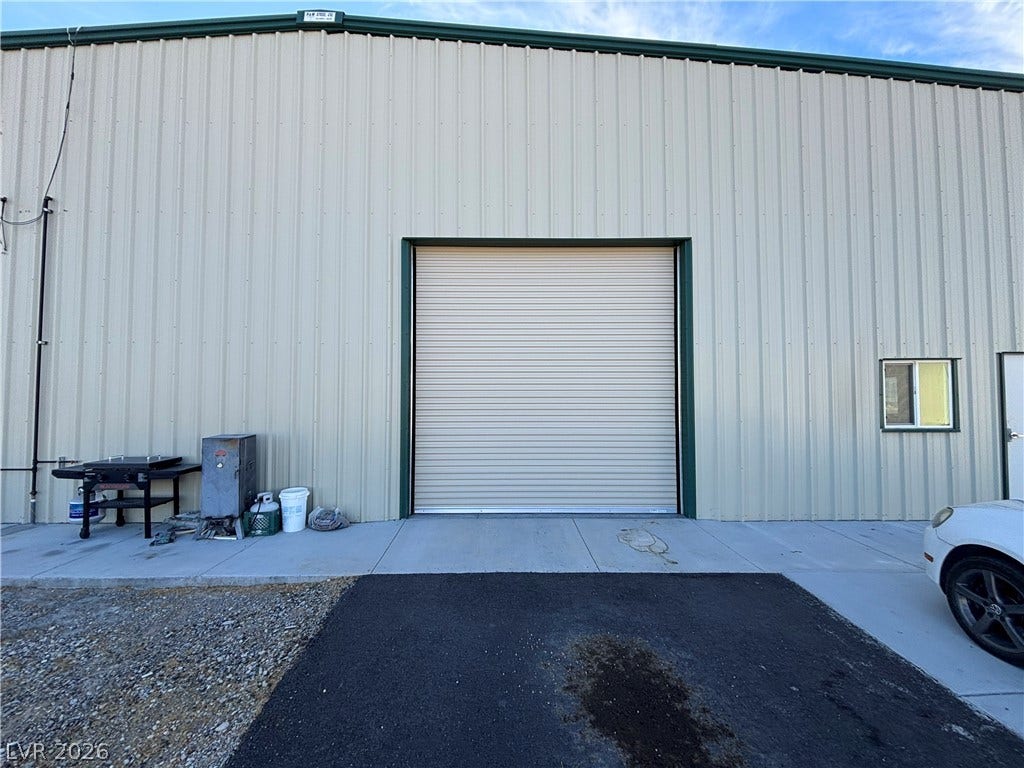 A spacious outbuilding features vertical metal siding and a large roll-up garage door.