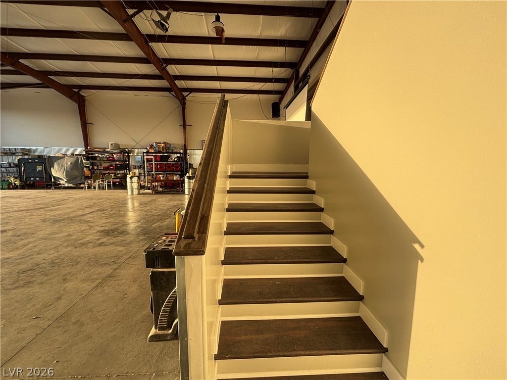 Rich wood treads and a sturdy handrail define this clean staircase ascending beside the workshop.