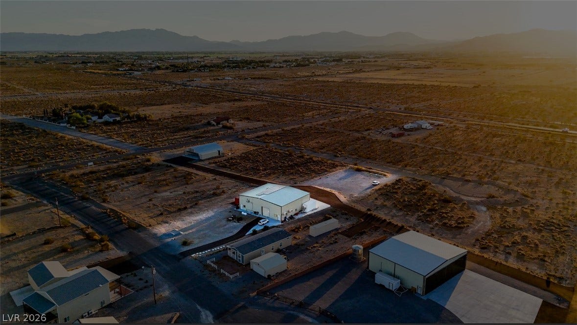 Dramatic mountain backdrops surround this expansive desert property featuring multiple outbuildings and residential structures.
