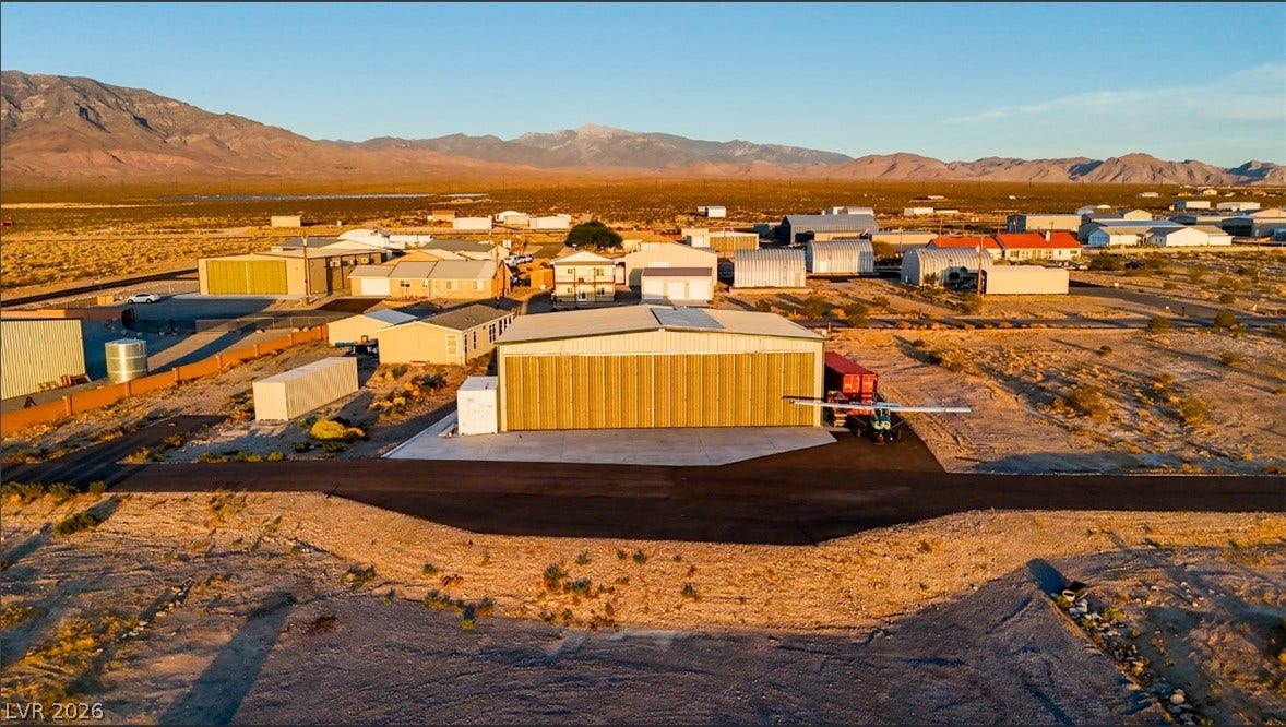 An expansive desert landscape frames this property with a private runway and hangar.