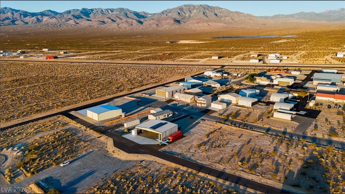 Dramatic mountain ranges frame a vast desert community equipped with private hangars and airstrip access.