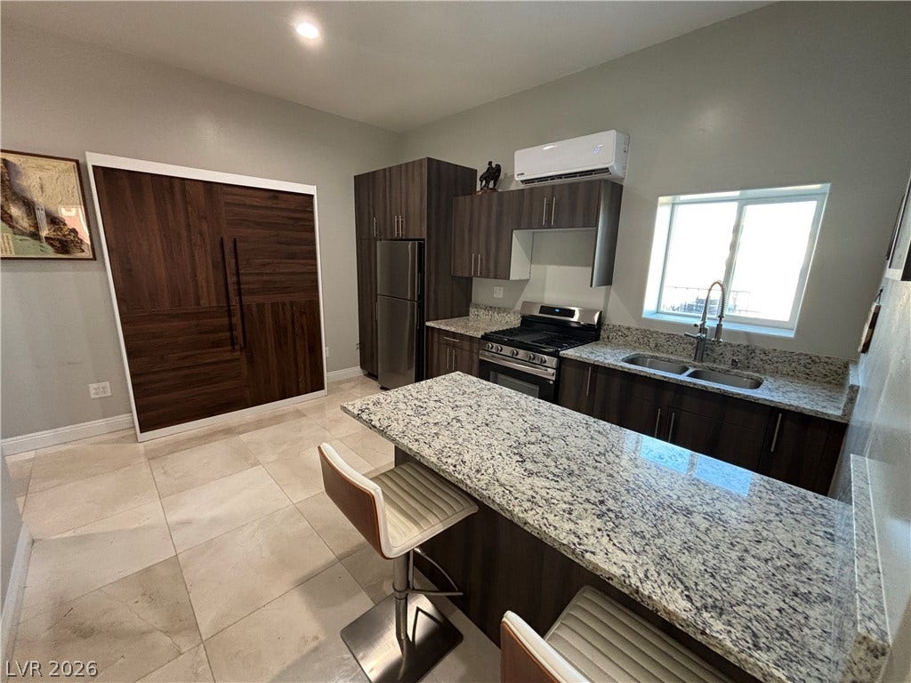 Granite countertops and dark wood cabinetry define this modern culinary workspace with tile flooring.