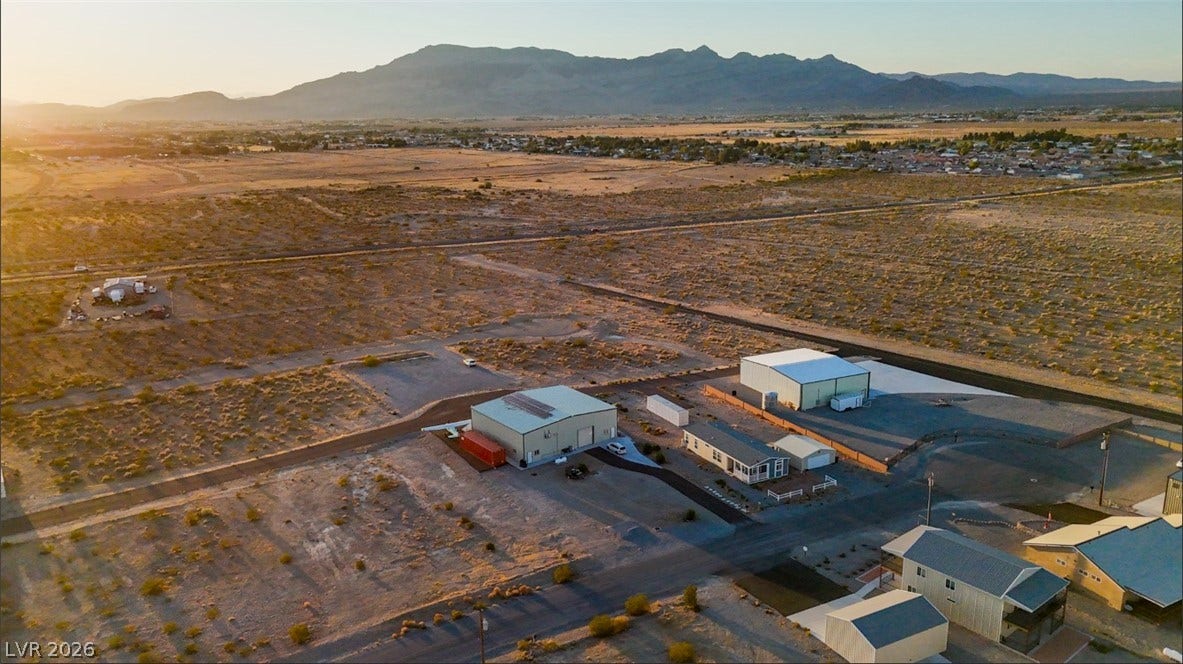 Dramatic mountain backdrops frame this expansive desert property featuring substantial outbuildings.
